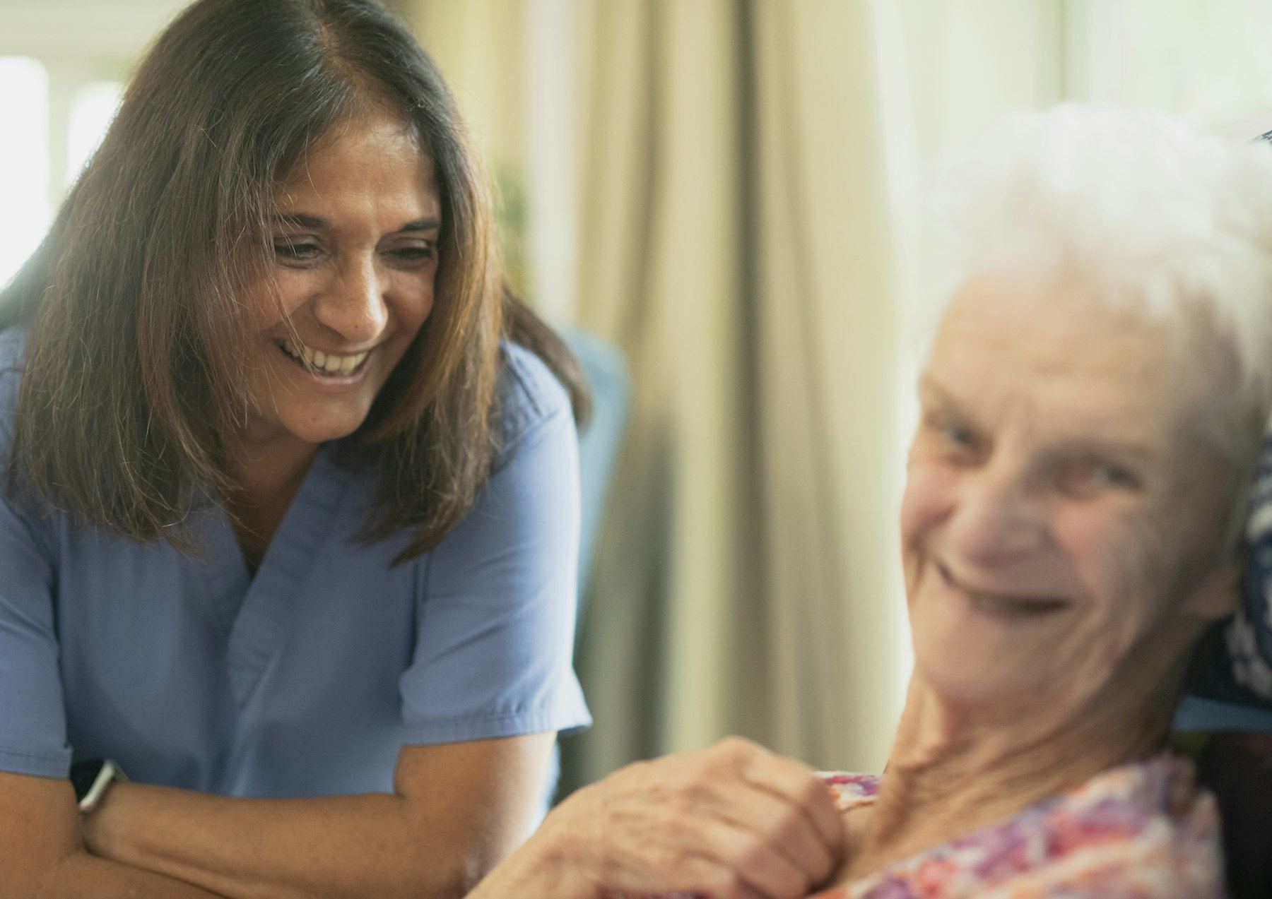 Cuidadora y residente compartiendo una charla y una sonrisa